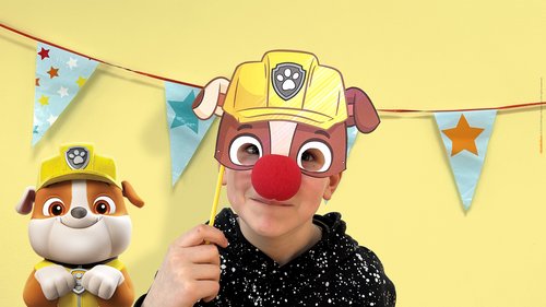 Ein kleines Kind mit witziger PAW Patrol Maske versucht, für ein Minispiel nicht zu lachen.