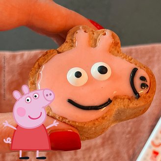 Peppa Pig Muffin zwischen zwei Fingern gehalten mit Peppa Pig