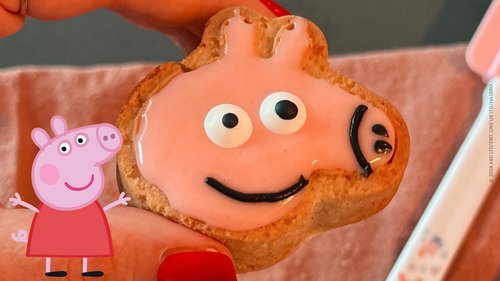 Peppa Pig Muffin zwischen zwei Fingern gehalten mit Peppa Pig